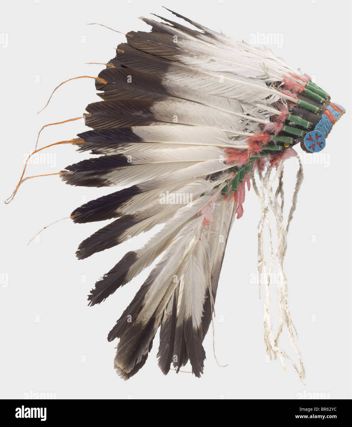 A Plains Indian war Bonnet, USA, Anfang des 20. Jahrhunderts. Eine Krone aus großen Adlerfedern, die untere mit rot gefärbten Daunenfedern verziert ist, die an einer Filzkappe befestigt sind. Die Stirnpartie ist mit farbigen Perlen bestickt. Höhe ca. 45 cm. Eine Kriegshaube wurde nur zu besonderen Anlässen getragen, die reichen Dekorationen berichteten von den siegreichen Kämpfen seines Besitzers. Allein die Adlerfedern waren sehr kostbar und hatten noch mehr Wert als gutes Pferd: Historisches, historisches Amerikanerchen, Amerika, Völkerkunde, Ethnie, Ethnie, Objekt, Objekte, Schnitten, Ausschneiden, Ausschneiden, Ausschneiden, Ware, Stockfoto