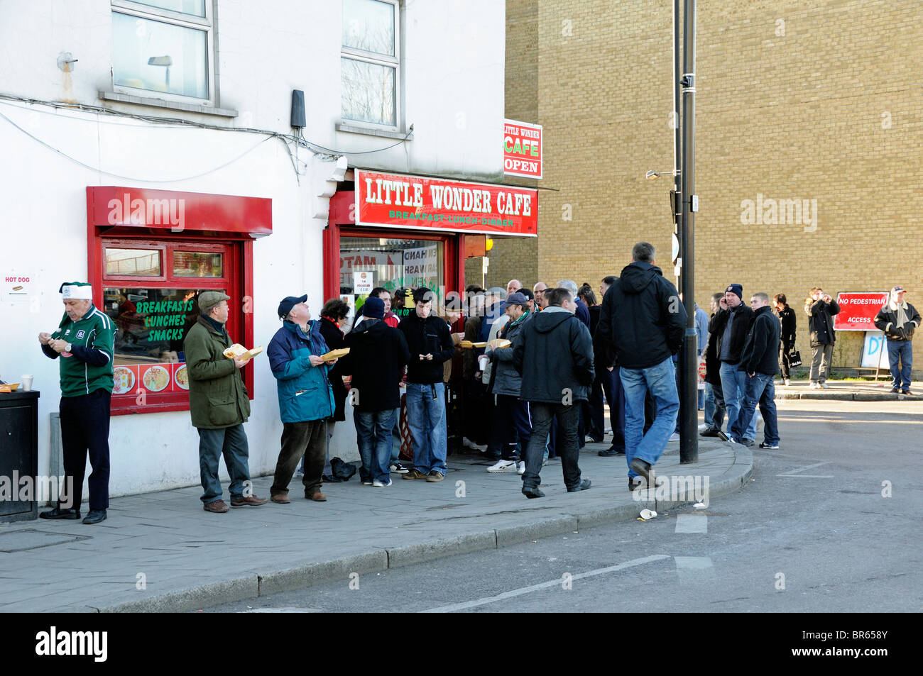 Fußballfans essen vor dem Little Wonder Café am Arsenal Football Club Spieltag Holloway London UK Stockfoto