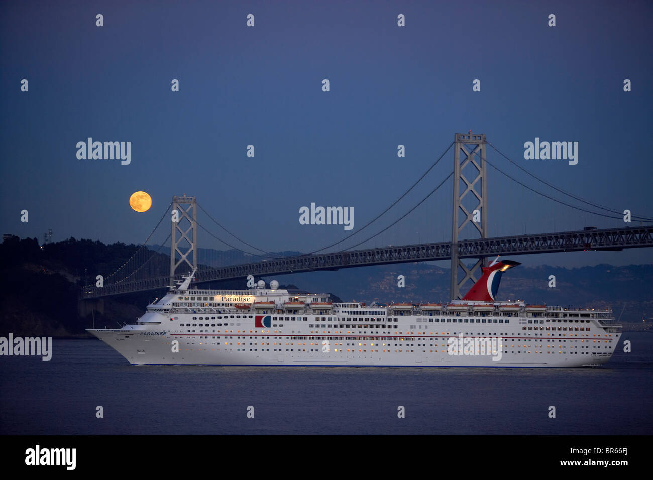 Ein Kreuzfahrtschiff, Unterquerung der Bay Bridge bei Nacht. Stockfoto