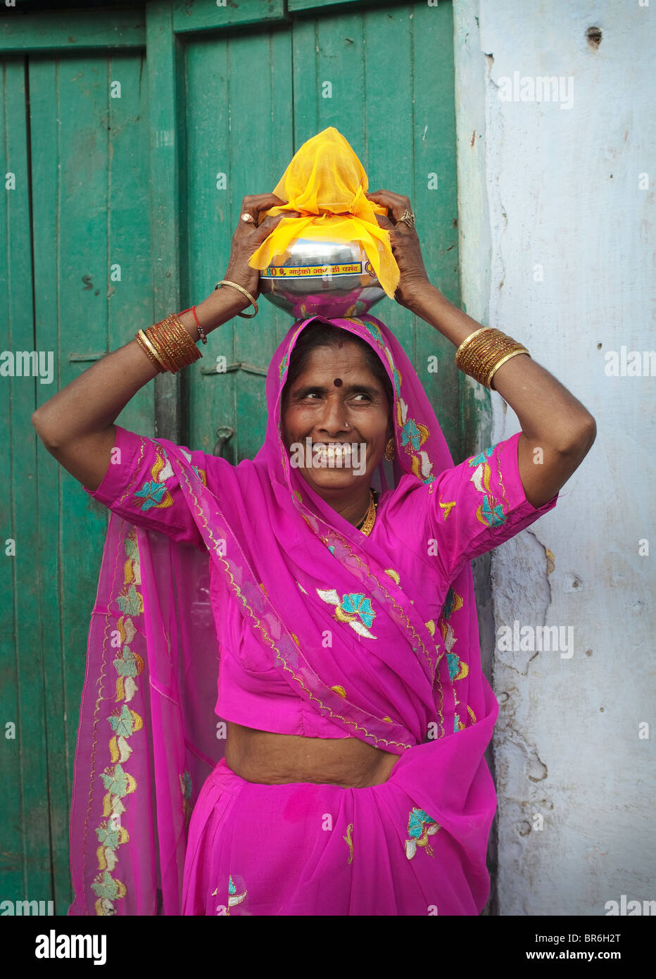 Ältere Frau (Sari trägt und hält eine Schüssel auf dem Kopf) auf einer Hochzeit, Indien. Stockfoto