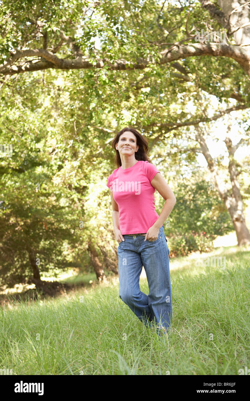 Junge Frau, die zu Fuß durch lange Rasen im Park Stockfoto