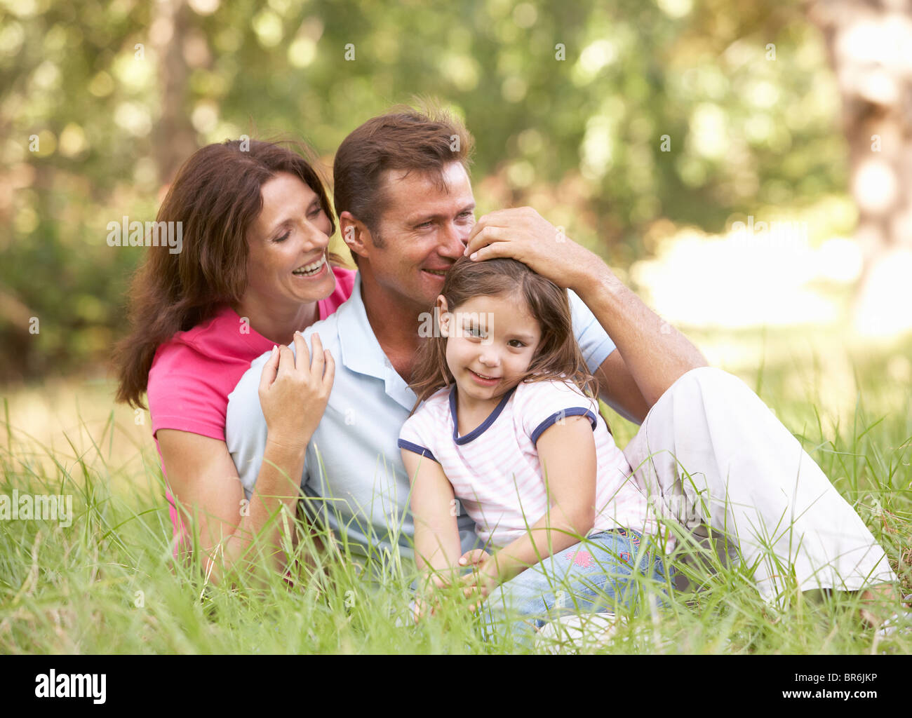 Familie sitzen In langen Rasen im Park Stockfoto