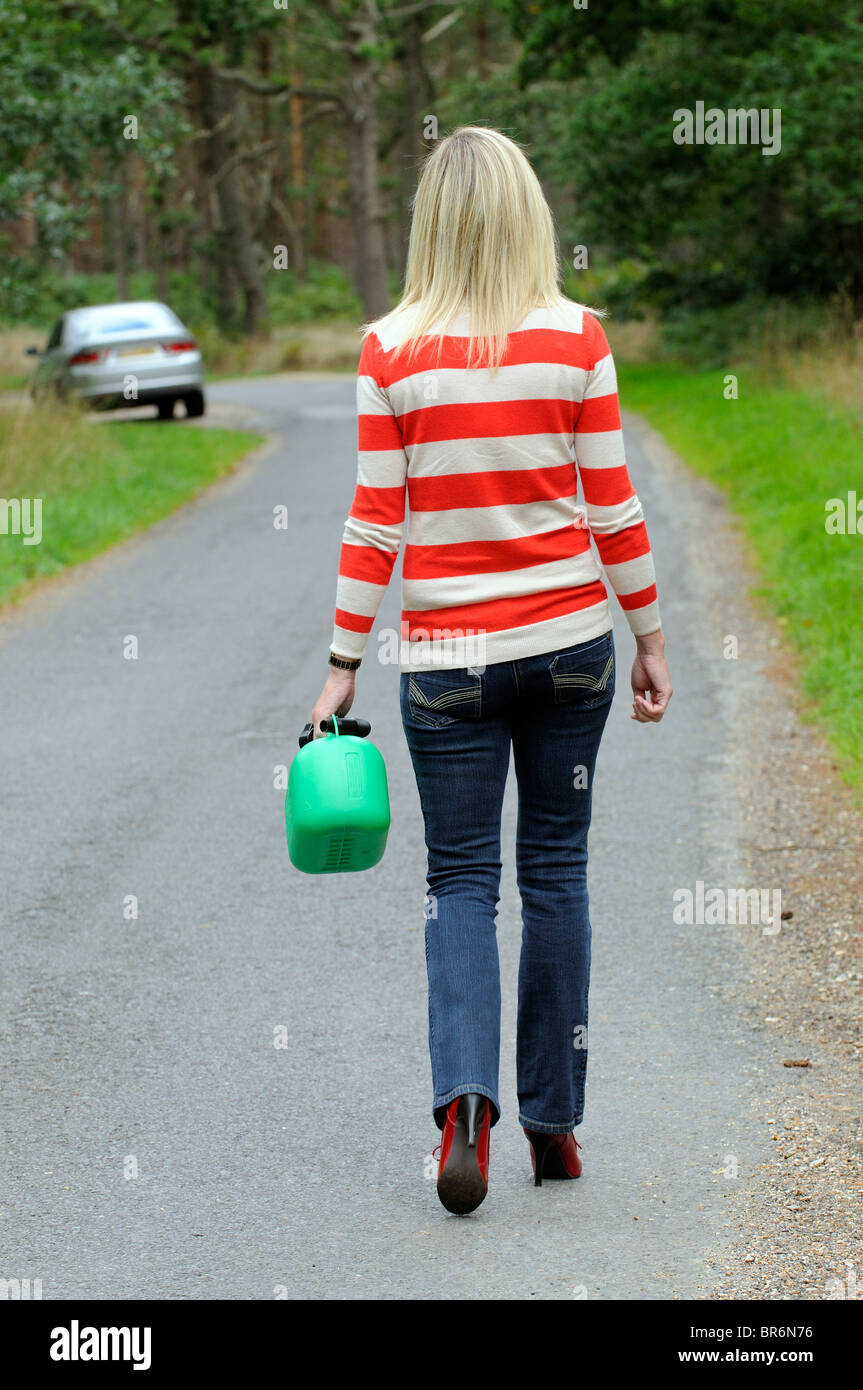 Weiblichen Autofahrer zu Fuß auf einer Landstrasse hält ein 5-Liter-Benziner kann Frau Autofahrer aus Kraftstoff heraus Stockfoto