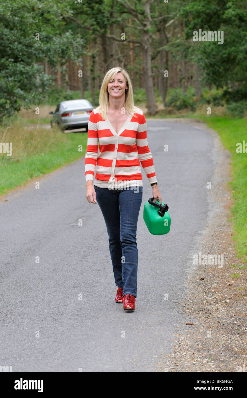 Weiblichen Autofahrer zu Fuß auf einer Landstrasse hält ein 5-Liter-Benziner kann Frau Treiber Treibstoff Stockfoto