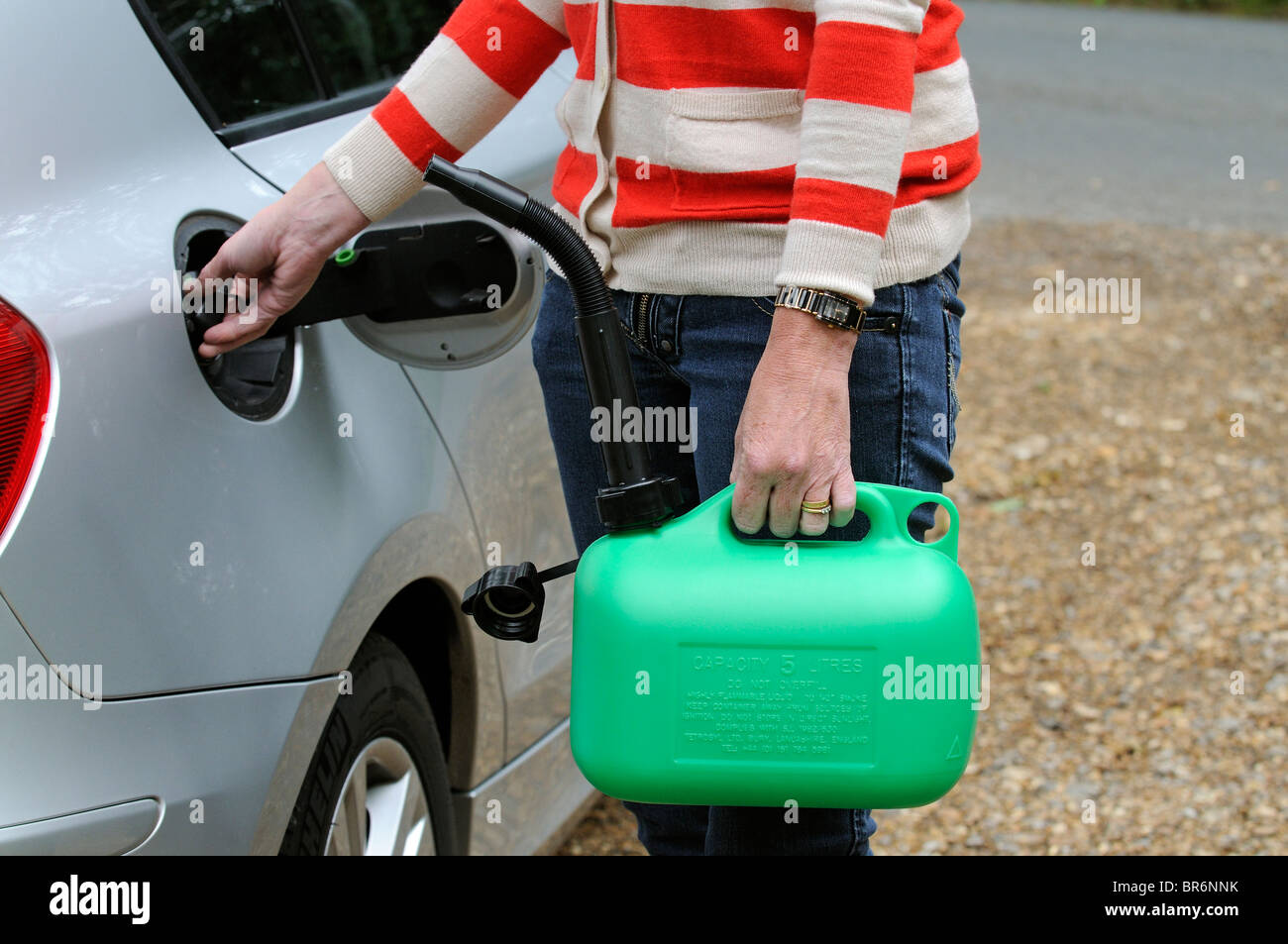 Weiblichen Autofahrer den Tankdeckel öffnen und ein 5-Liter-Benziner halten können Stockfoto