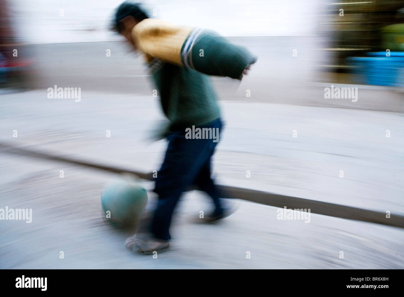 Ein kleiner Junge spielt Fußball auf der Straße in Pisac Peru (Motion Blur). Stockfoto