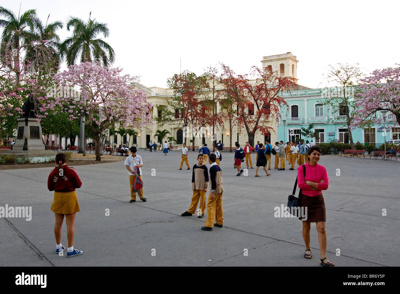 Schulkinder verweilen auf einem platz, umgeben von blühenden Bäumen in Santa Clara Kuba. Stockfoto