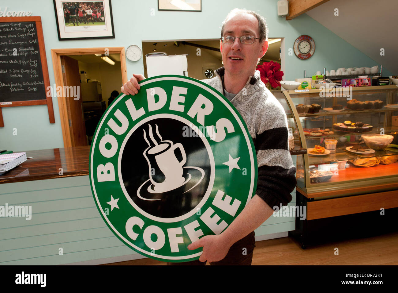 DEREK EDWARDS, der Besitzer von Felsbrocken Cafe, Borth, Wales UK, mit dem Zeichen für sein Café, das er gehabt hat, zu entfernen Stockfoto