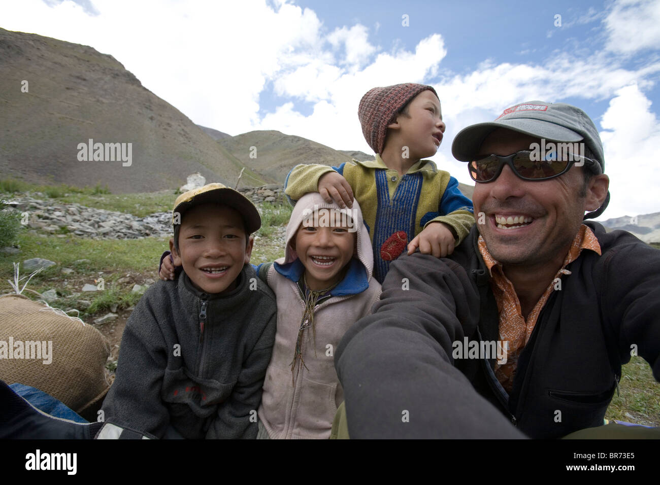 Kaukasischen Mann lächelt, 35-45 Jahre alt mit einheimischen Kindern in Zanskar-Bergen im Norden Indiens. Stockfoto