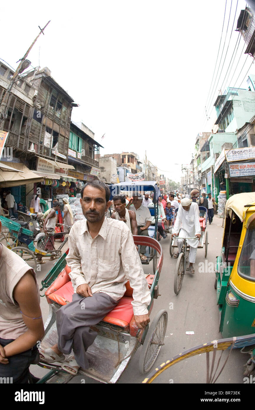 Indischer Mann reitet in Rikscha auf belebten Straße in Delhi-Indien. Stockfoto