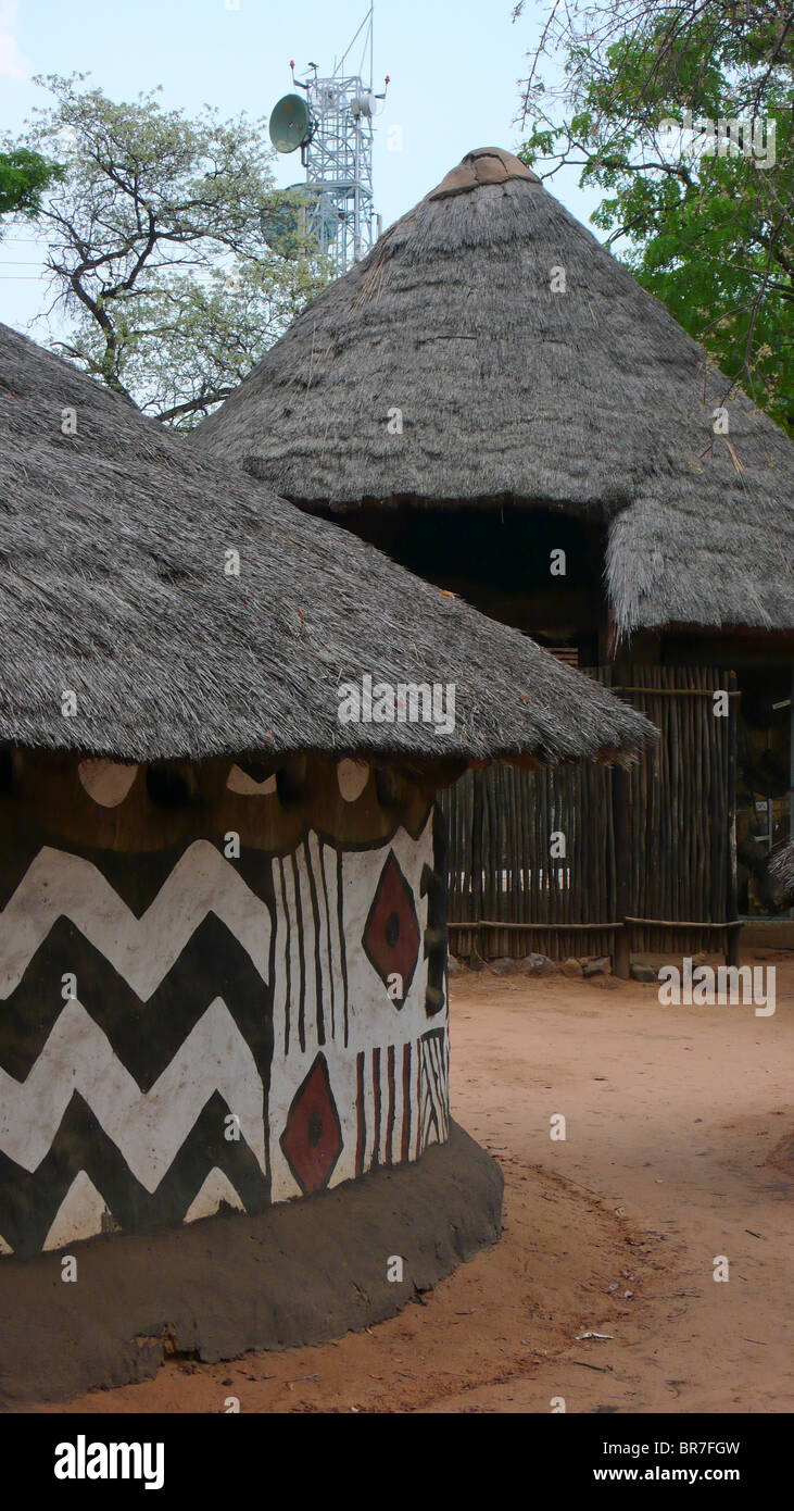 Traditionellen Schlamm und Reetdach Häuser sitzen vor einem Fernmeldeturm in Victoria Falls Town Simbabwe. Stockfoto