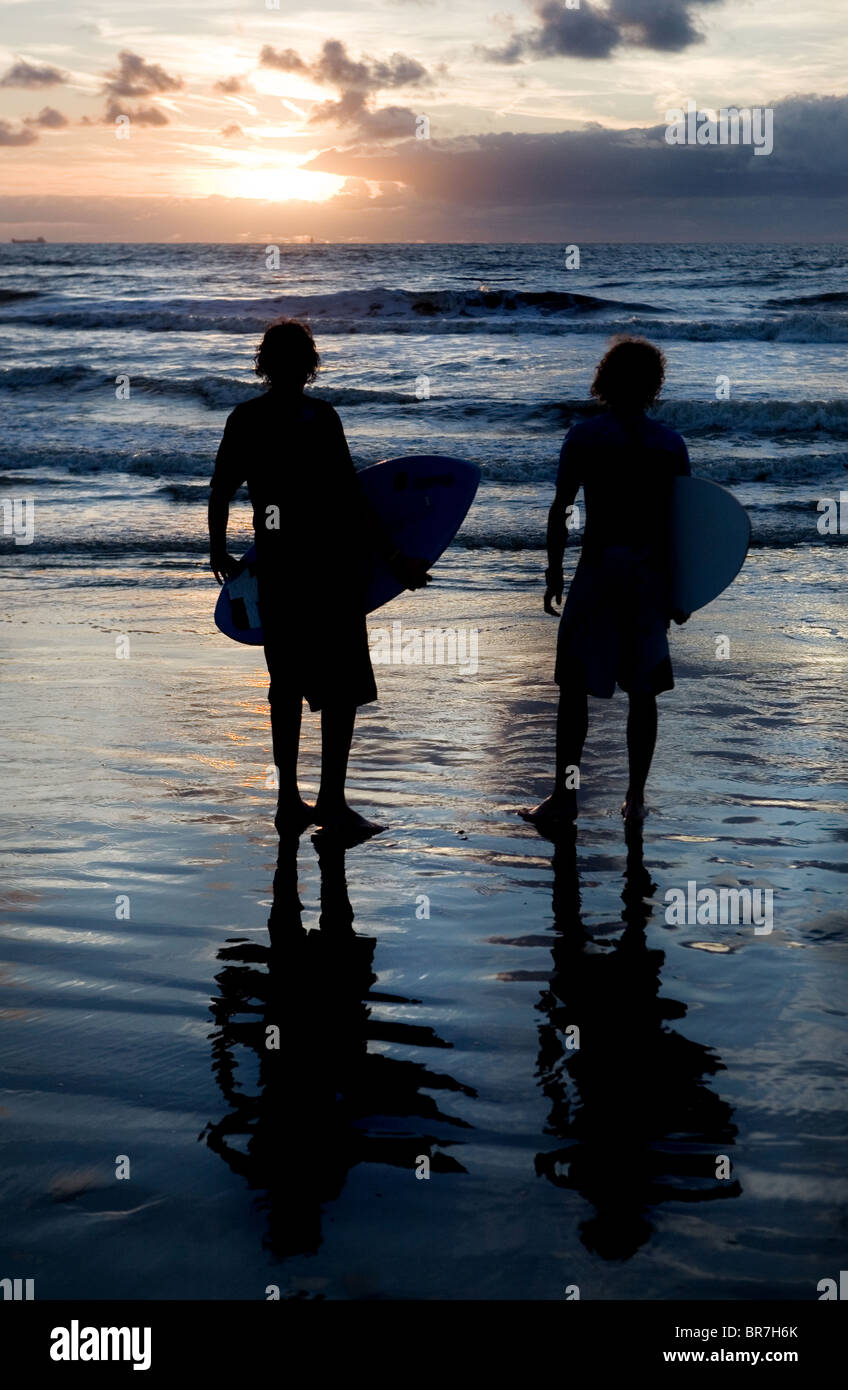 junge Burschen, die den Sonnenuntergang am Strand hinunter Stockfoto