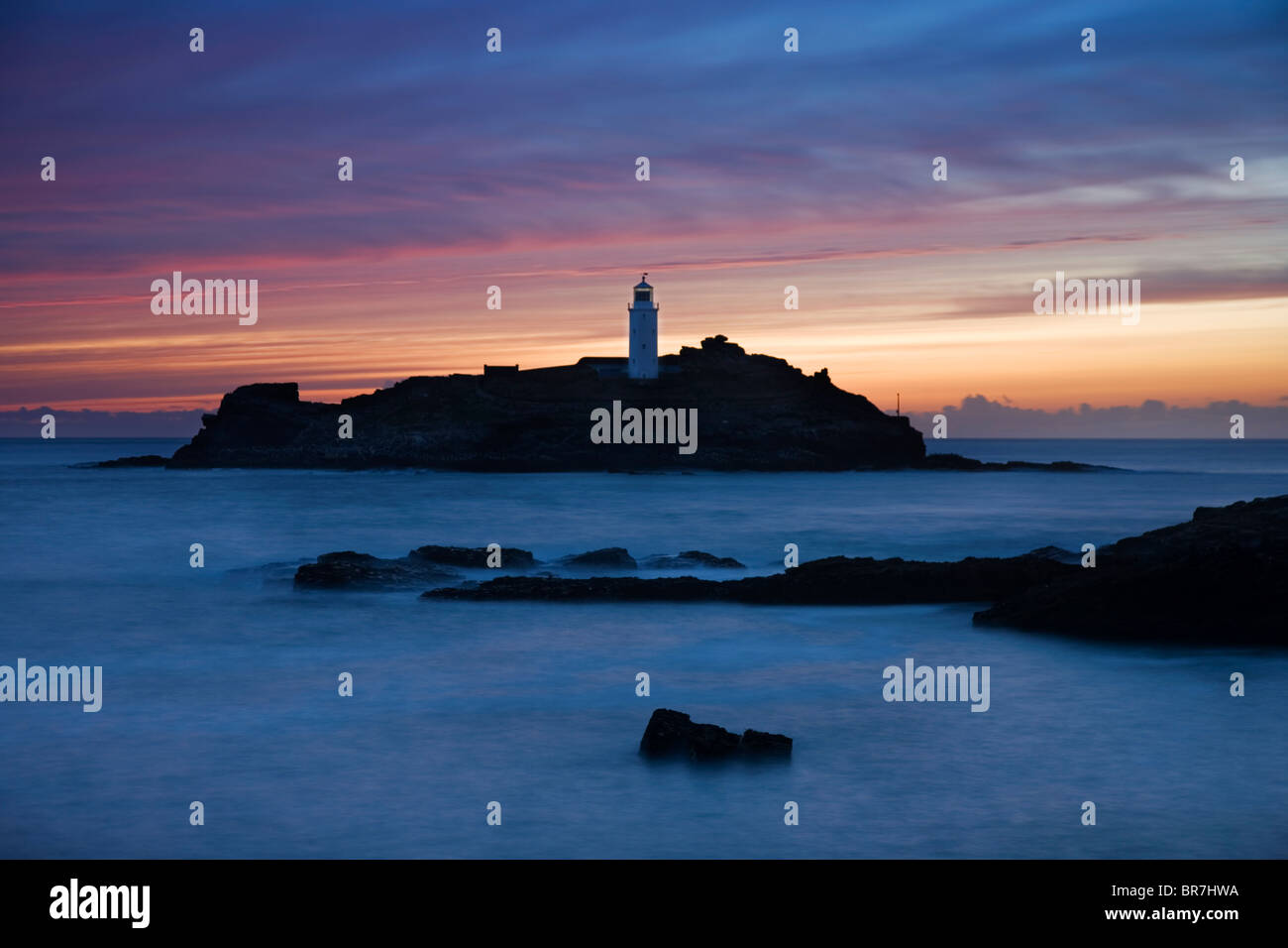 Blick über den Felsen Godrevy Lighthouse Point bei Sonnenuntergang mit brechenden Wellen St Ives Bay Cornwall UK Stockfoto