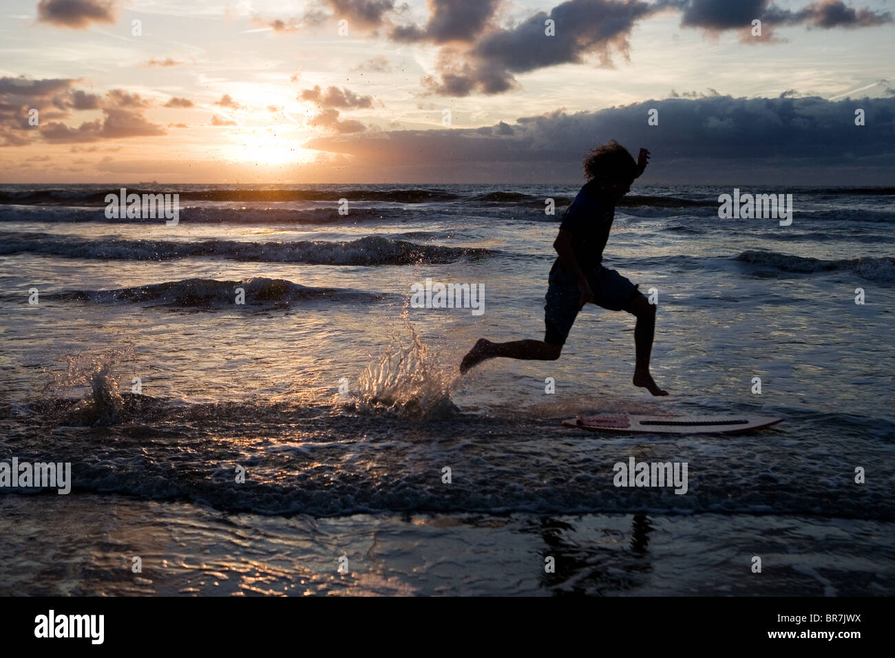 Junge springt auf Skim Board an der niederländischen Küste Stockfoto