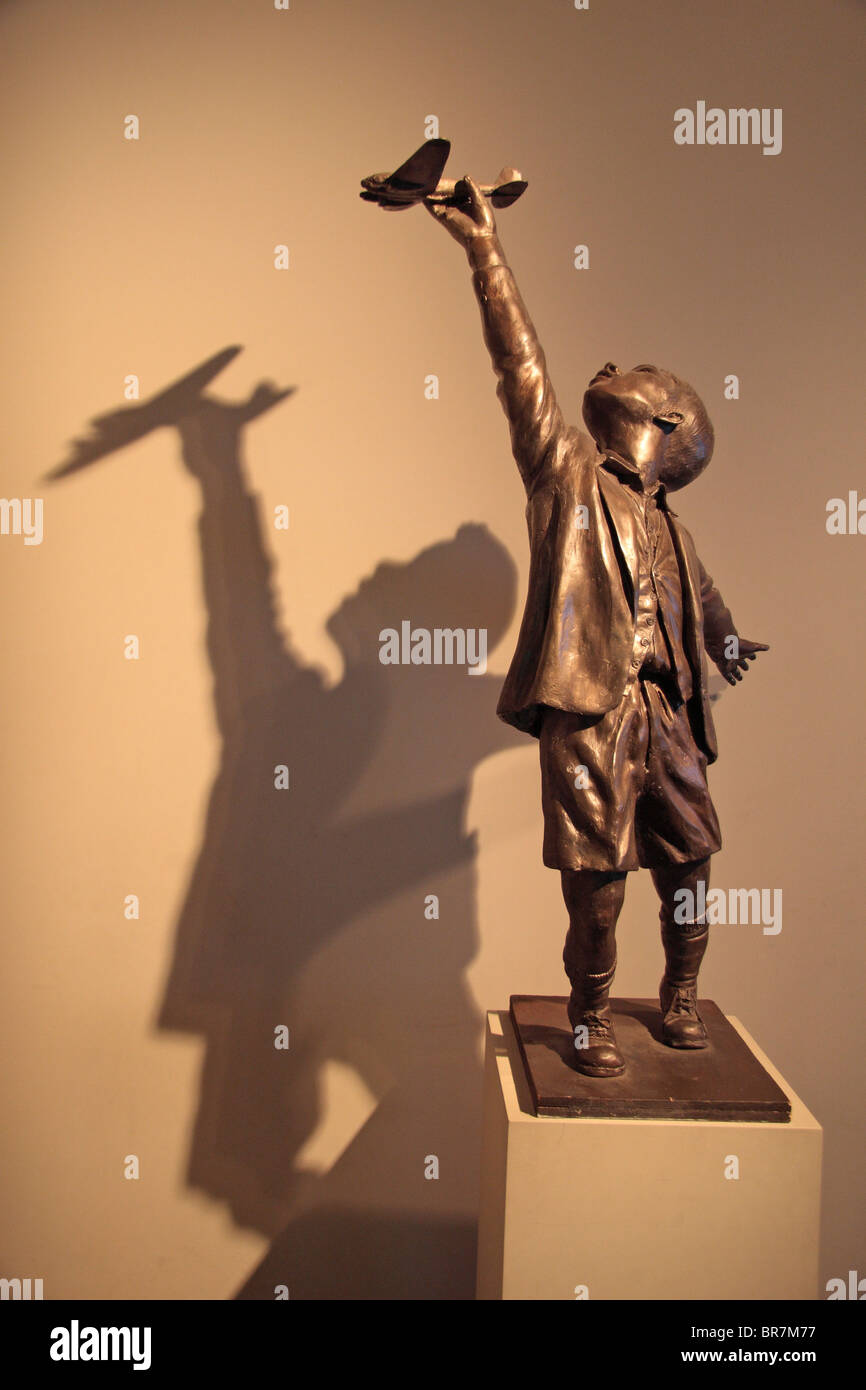 Eine bronzene Skulptur und Schatten eines jungen hält ein Spielflugzeug im Imperial War Museum London ausgestellt. Stockfoto