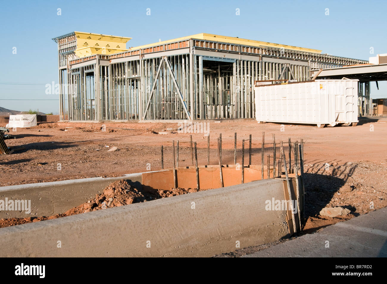 Ein Rahmen von Baustahl ist konstruiert, um eine Wand in ein neues Bankgebäude zu unterstützen. Konkrete Bordstein Formen im Vordergrund. Stockfoto