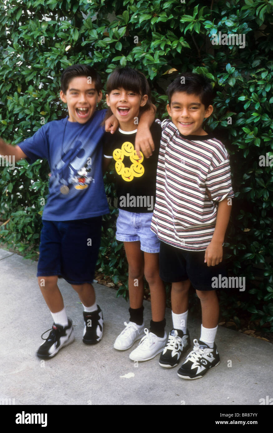 Hispanische Twin Mädchen Jungen großen älteren Bruder Lächeln Umarmung Lachen Spaß Liebe Shorts Sommer Aktie Touch Verhalten Stockfoto