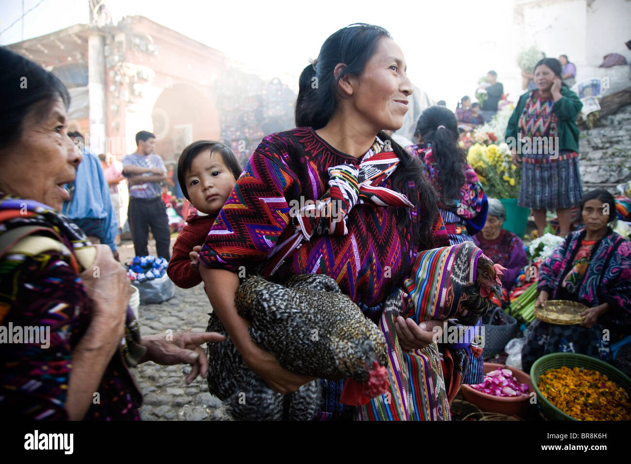 Eine Frau trägt ihr Kind und Hühner in Chichicastenango Markt. Stockfoto