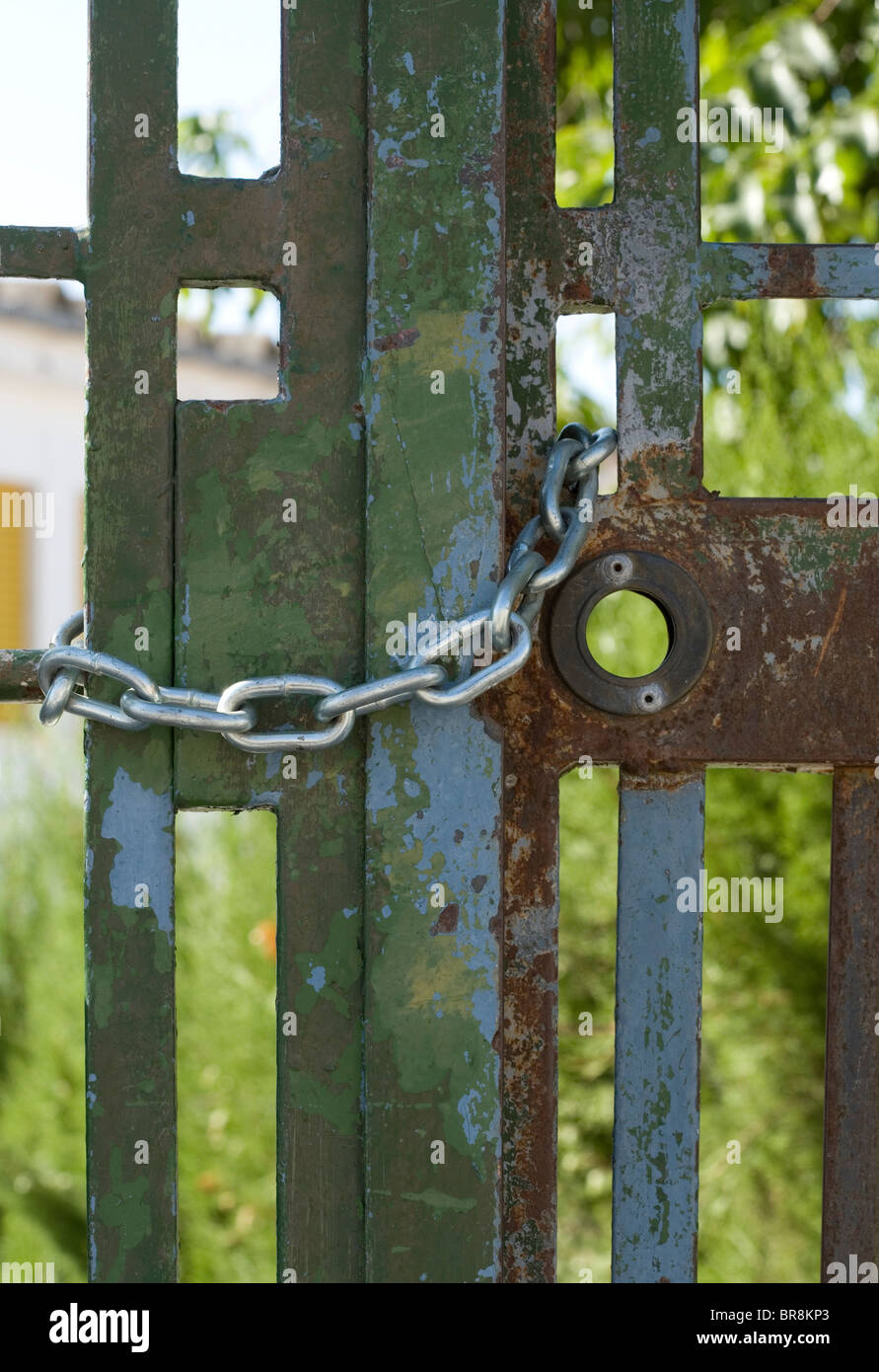 Kette halten enge eine metallische Gate mit einer Eigenschaft im Hintergrund Stockfoto