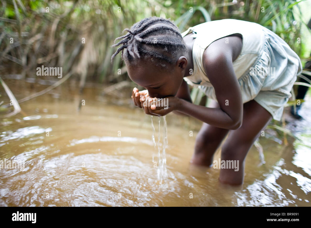 Liberianische Mädchen Trinkwasser Aus Einem Schmutzigen Strom Stockfoto 