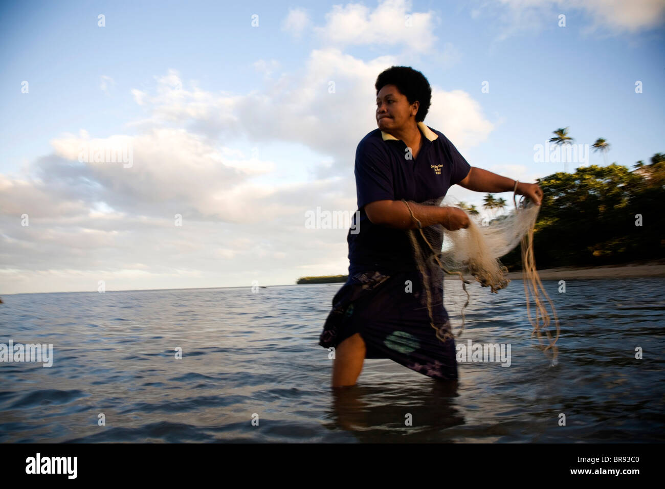 Eine Frau fischt mit einem kleinen Netz in den frühen Morgenstunden. Stockfoto