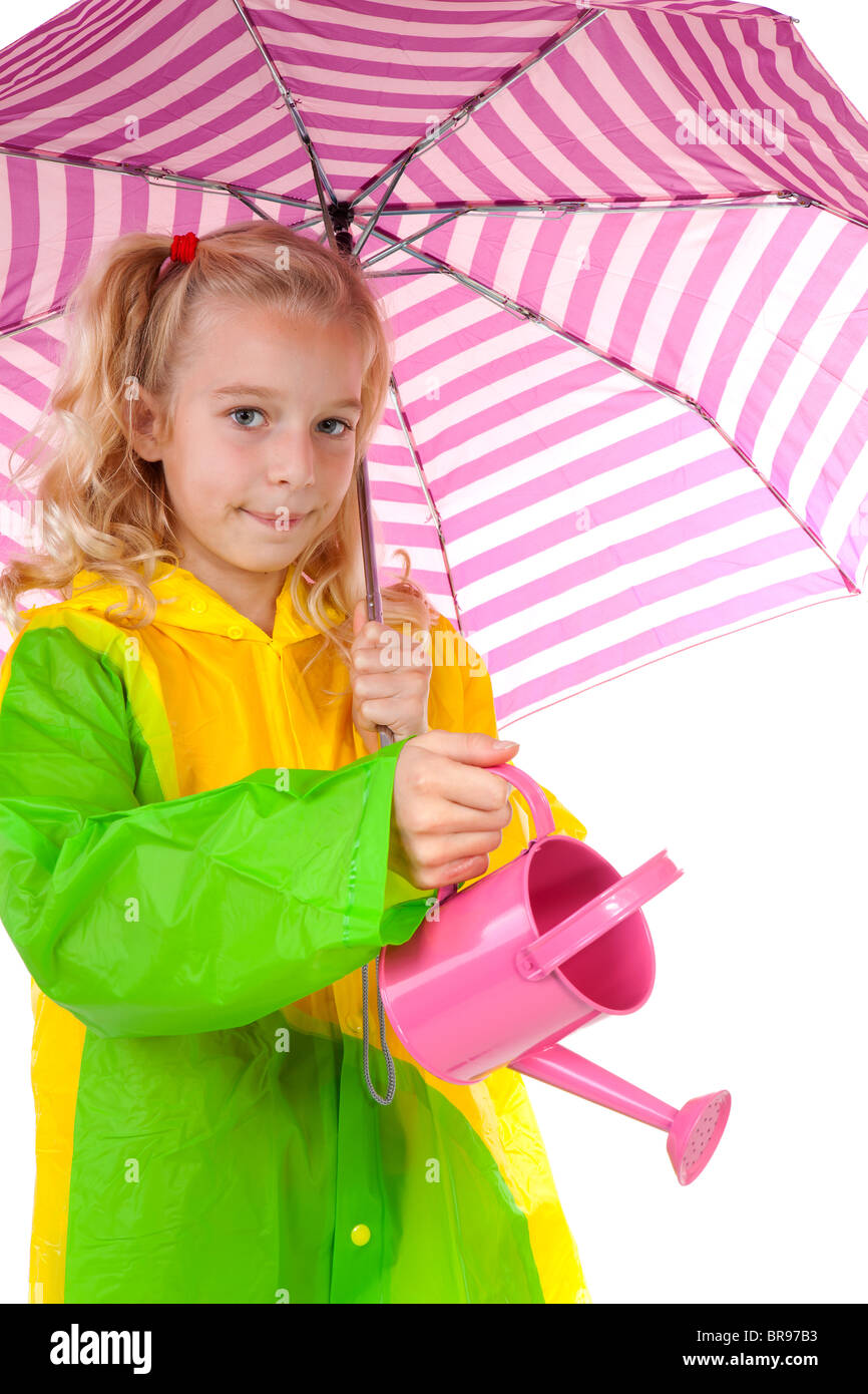 Junges blondes Mädchen bewässert die Pflanzen unter Dach im Regenmantel über weißem Hintergrund Stockfoto