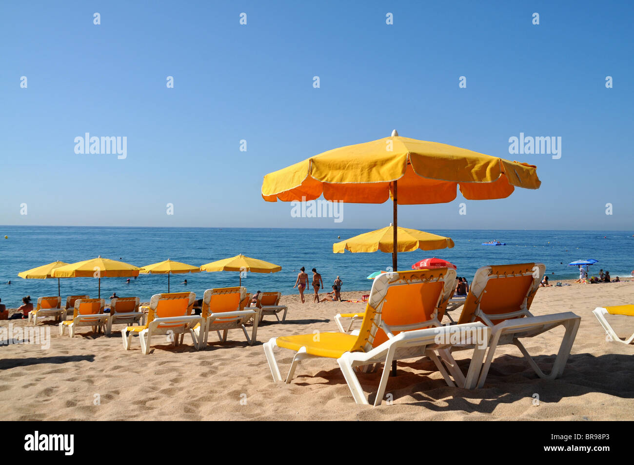 Strandkörbe / Sonnenliegen und Sonnenschirme am Strand von Calella vom Mittelmeer. Stockfoto