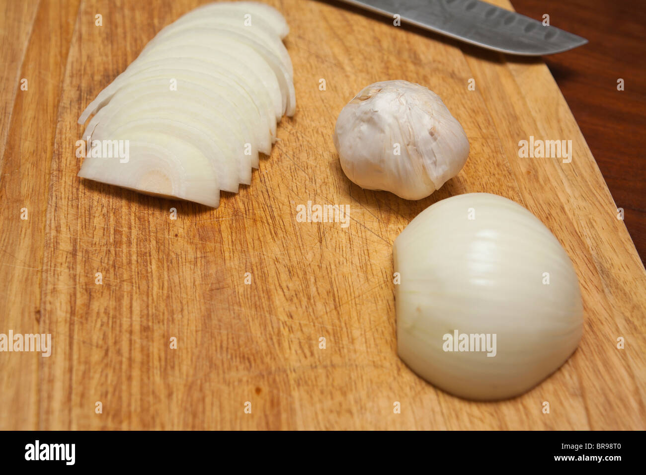 Zwiebel Knoblauch und Messer auf Schneidebrett Stockfoto