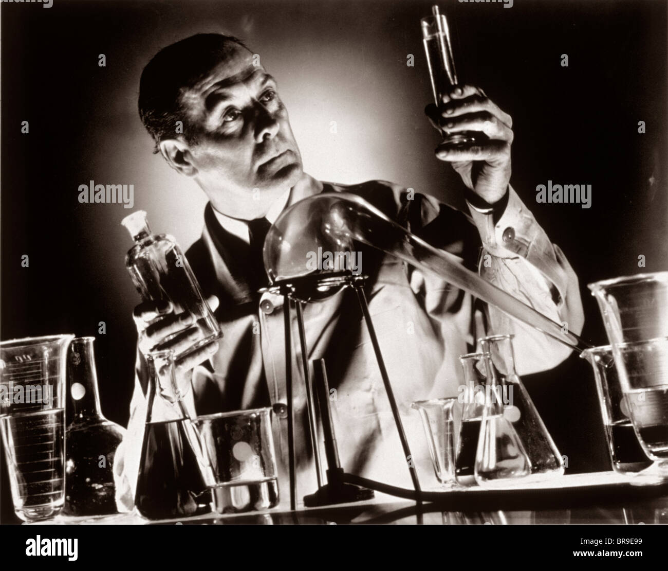 1930ER JAHREN WISSENSCHAFTLER CHEMIKER HÄLT REAGENZGLAS FLÄSCHCHEN BECHER IM LABOR Stockfoto