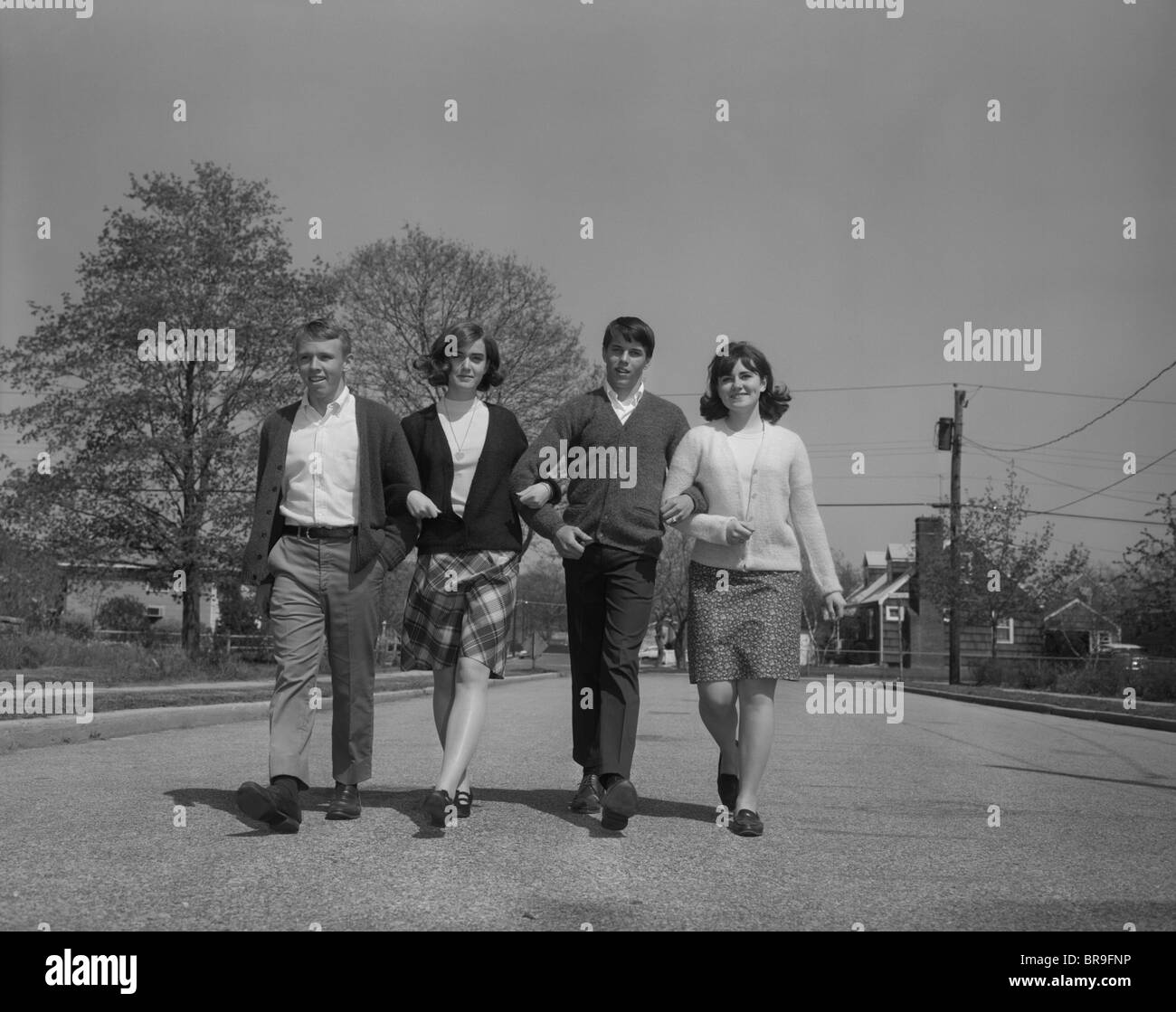 1960ER JAHREN ZWEI JUNGE TEEN PAARE GEHEN ZUSAMMEN ARM IN ARM AUF DER SUCHE IN DIE KAMERA Stockfoto