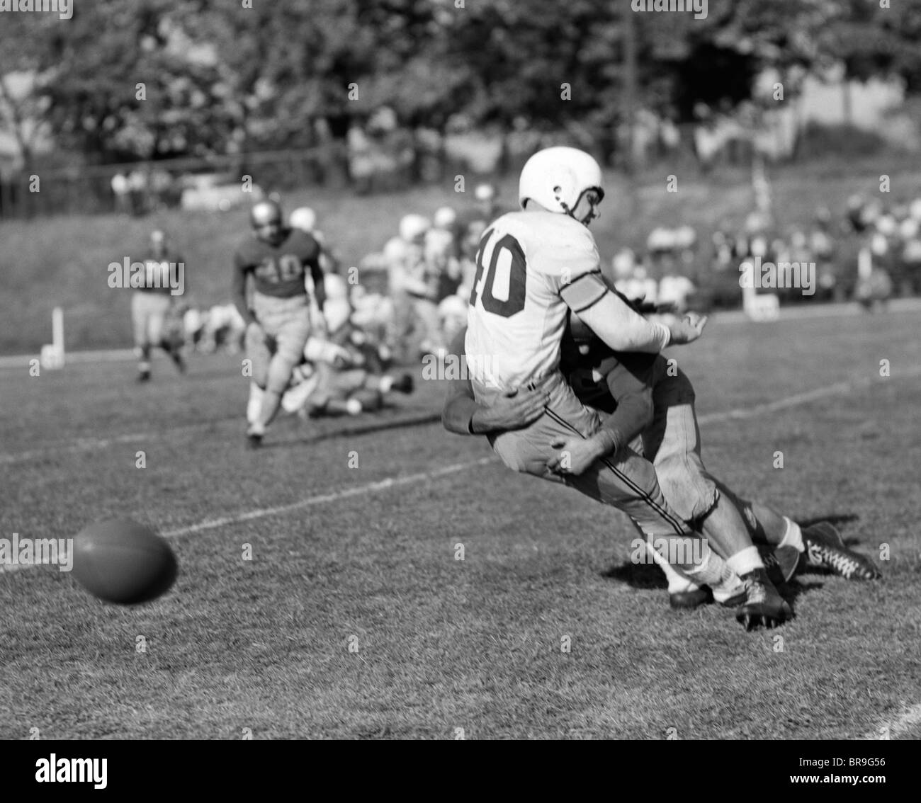 1950ER JAHRE COLLEGE FOOTBALL SPIEL EIN SPIELER KAMPF GEGEN EINEN ANDEREN FUMMELN Stockfoto
