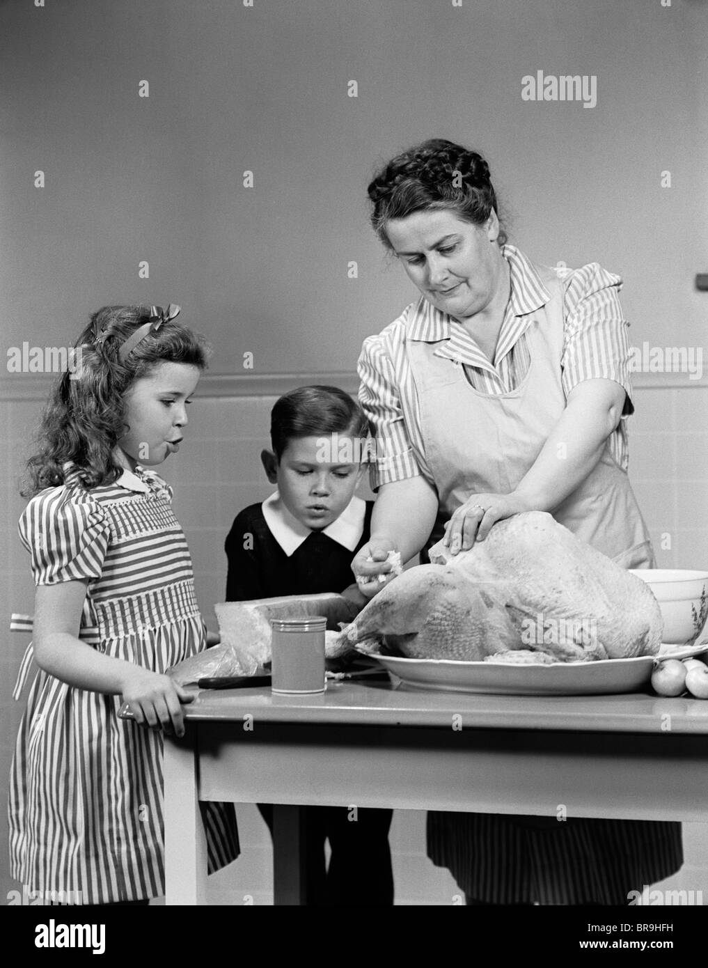 1940ER JAHRE MUTTER SOHN TOCHTER IN DER KÜCHE FÜLLUNG TÜRKEI FÜR THANKSGIVING-DINNER Stockfoto