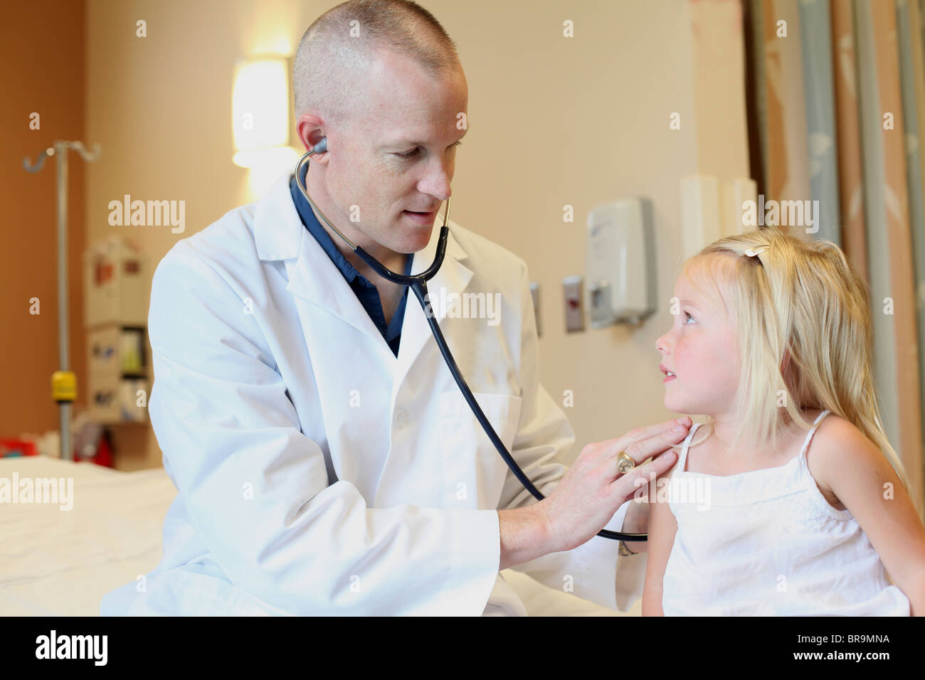 Junge Kinderarzt hört jungen Mädchens Atmung Stockfoto
