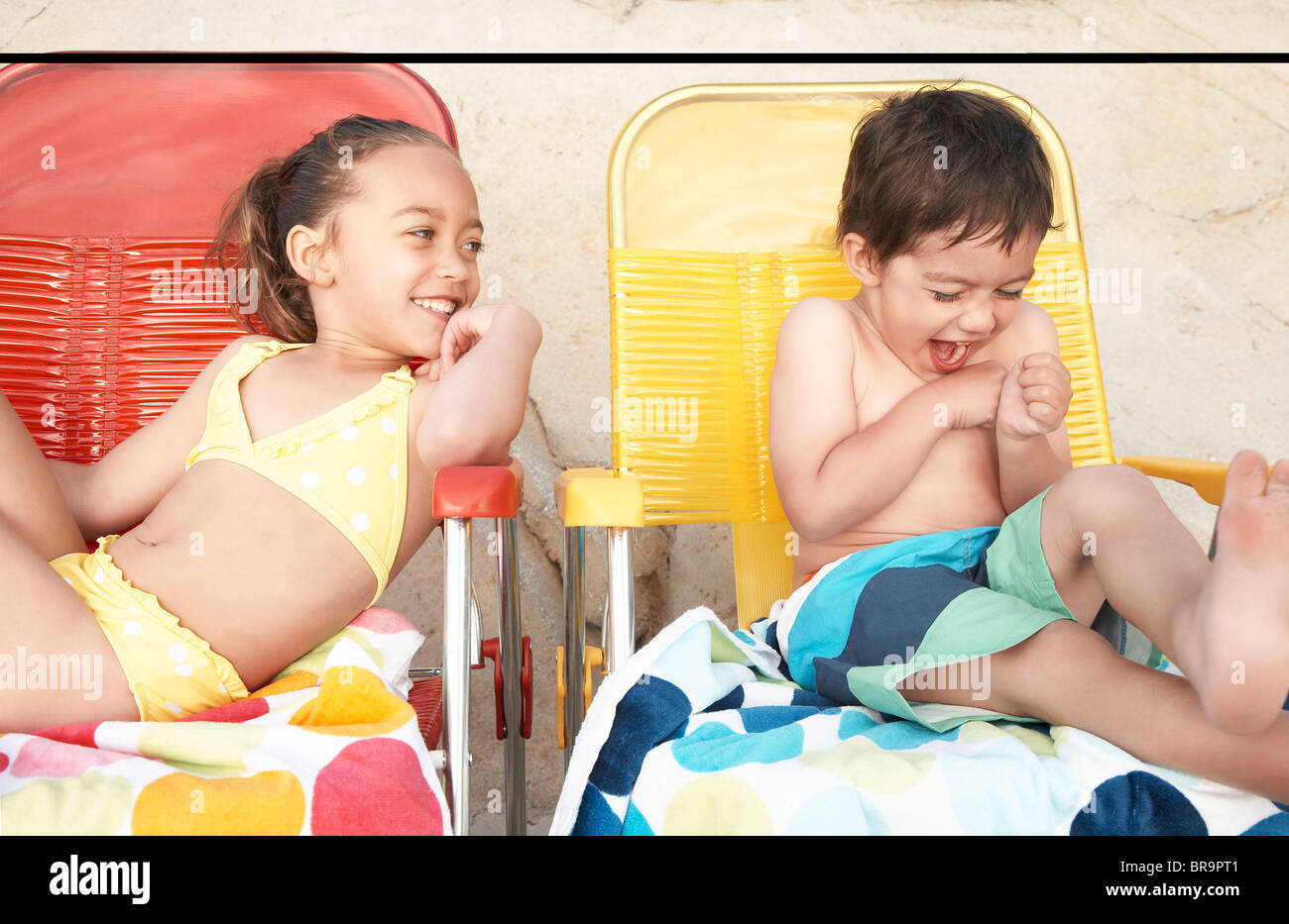 Kinder in Badeanzügen auf Liegestühlen Stockfoto