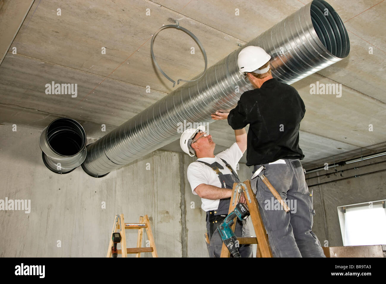 Zwei Lüftung Monteure installieren ein Entlüftungsrohr Stockfoto