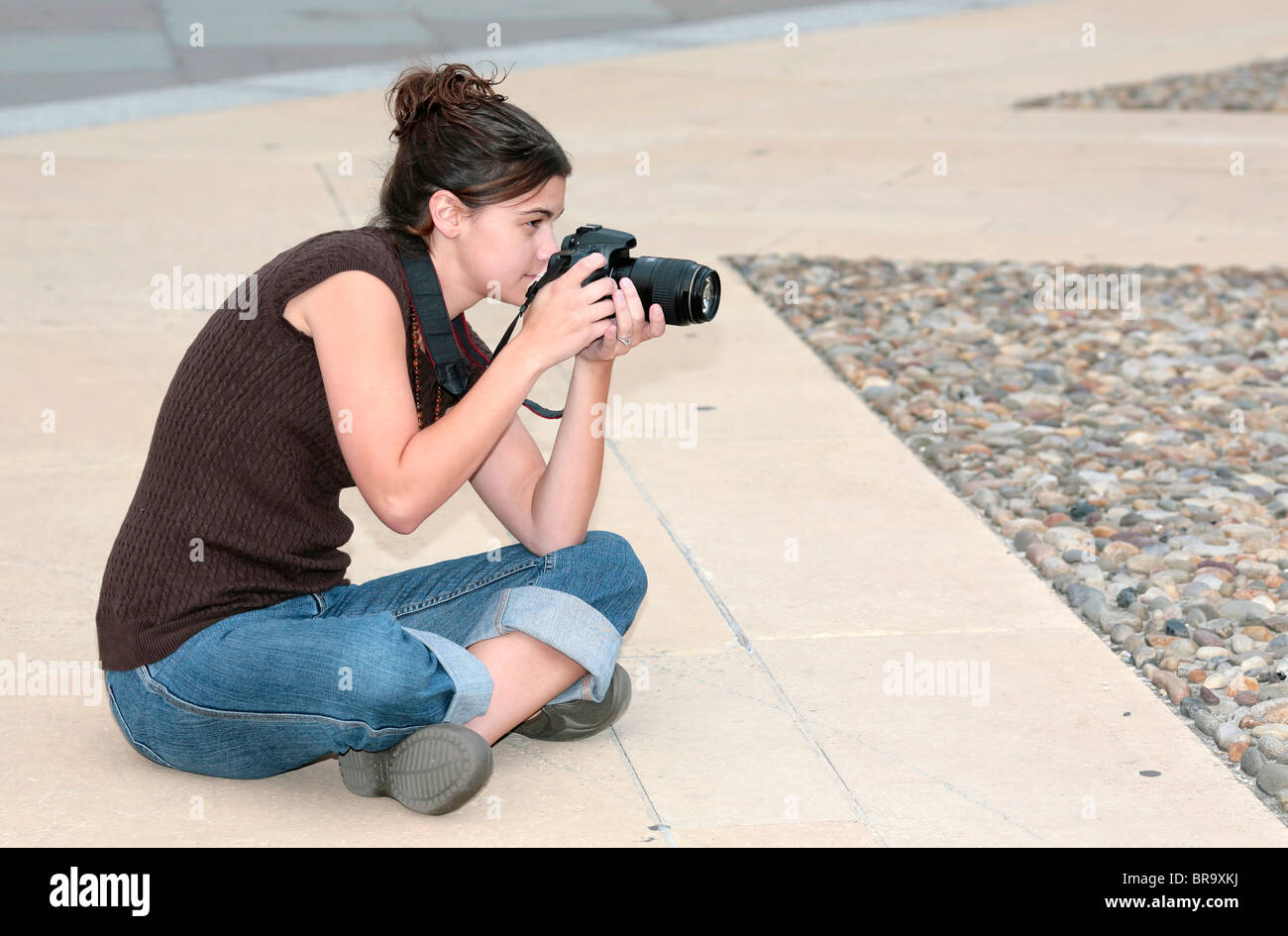 eine dünne Brünette Frau sitzend Fotografieren in der Stadt Stockfoto