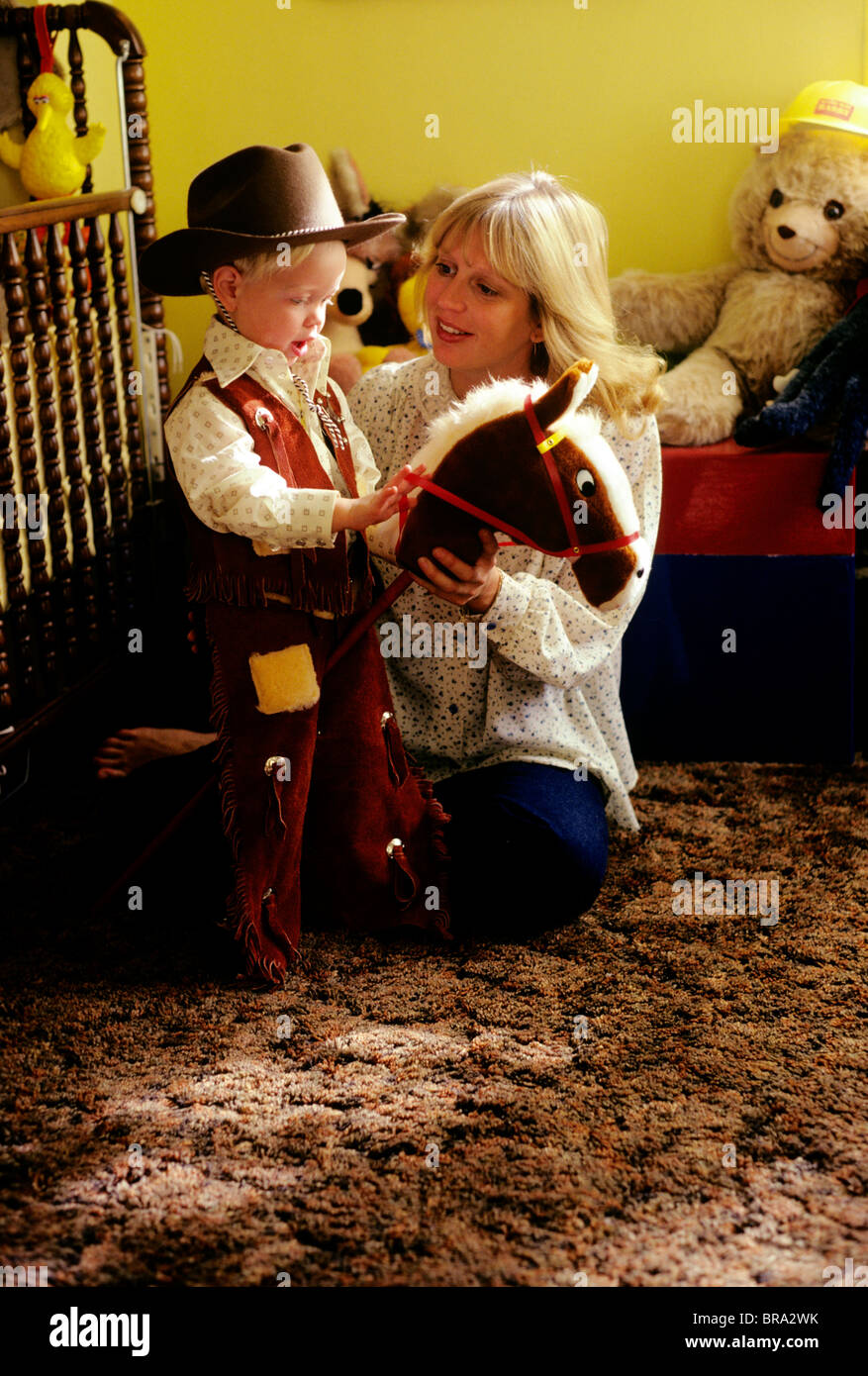 1981 1980S RETRO-MUTTER UND SOHN KRIPPE SCHLAFZIMMER COWBOY KOSTÜM Stockfoto