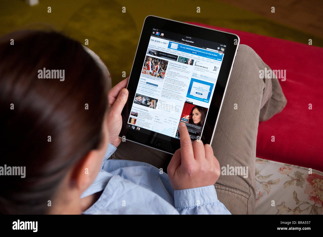 Frau mit iPad Tablet-Computer zu Hause, die australische Zeitung zu lesen Stockfoto
