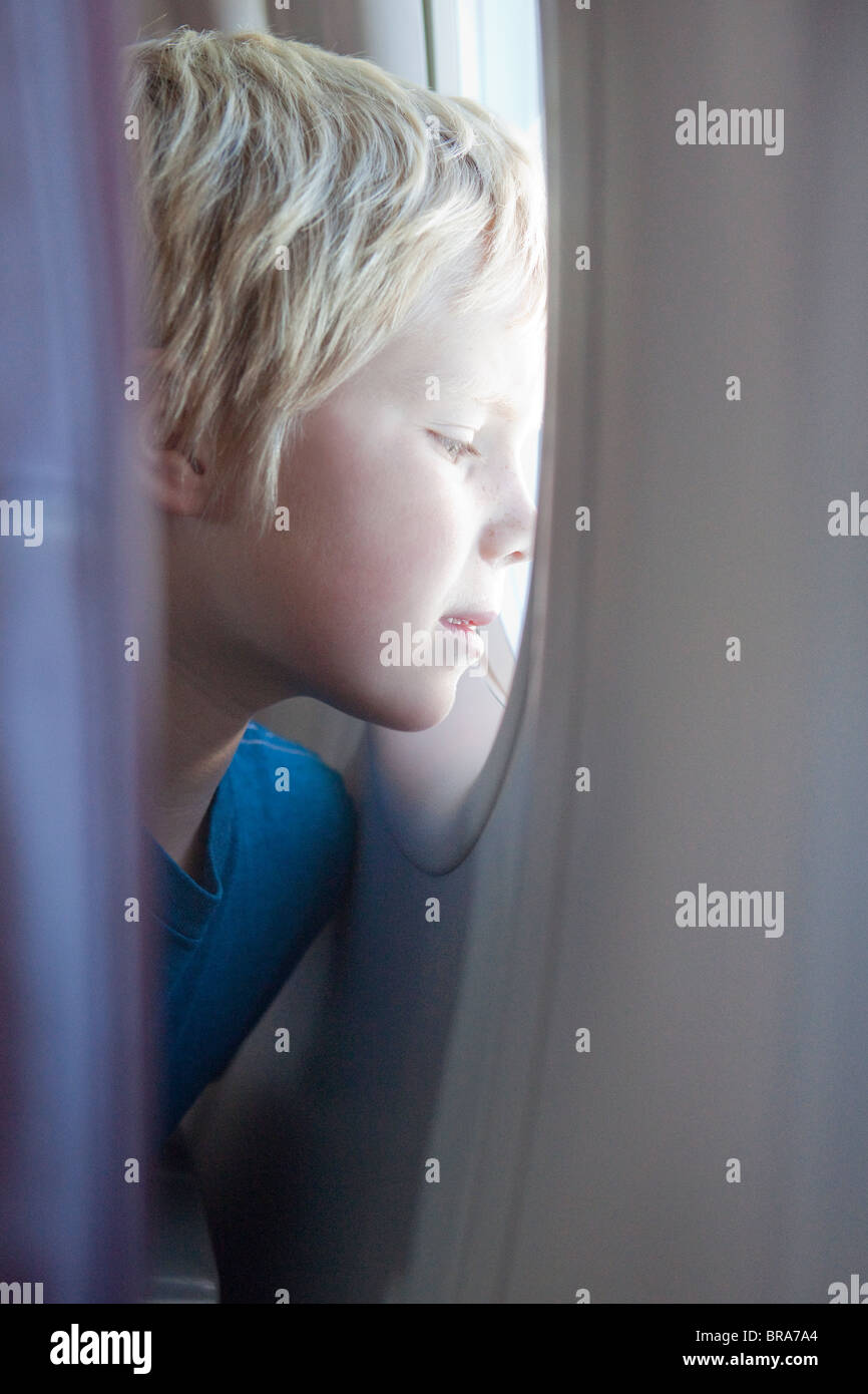 Kleiner Junge starrt Flugzeugfenster Stockfoto