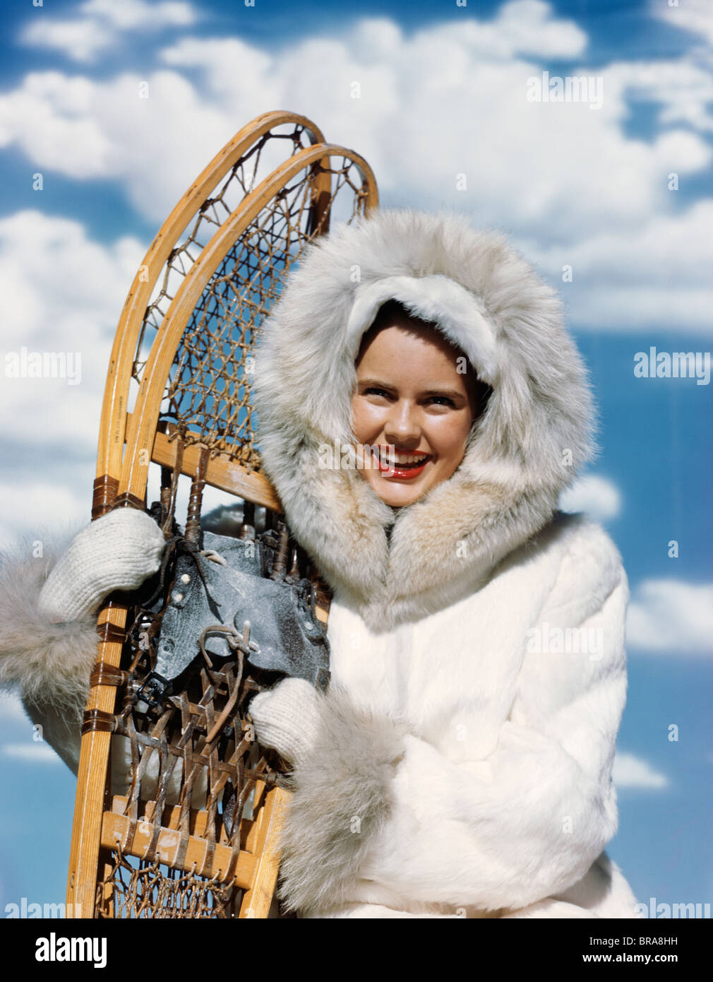 1940S 1950S FRAU WEIßES FELL PARKA HOLDING PAAR SCHNEESCHUHE Stockfoto