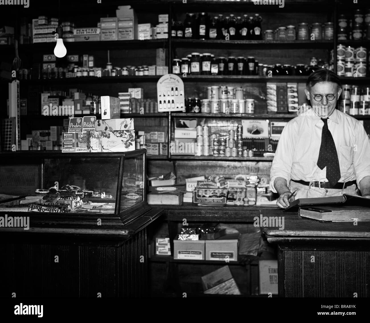 1930ER JAHRE ALLGEMEINE INNERE LEBENSMITTELHÄNDLER LADENBESITZER TRESEN Stockfoto
