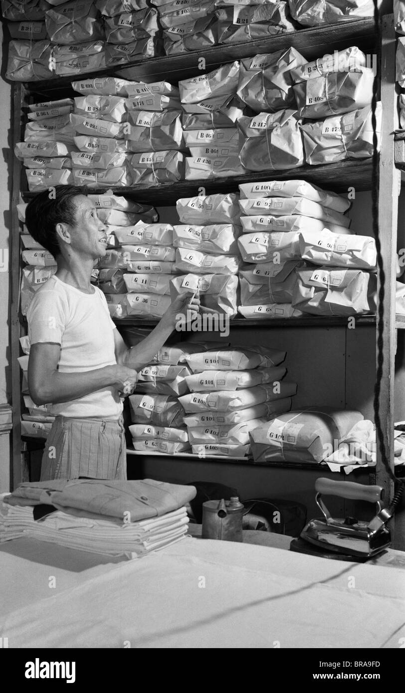 1940ER JAHREN ASIATISCHER MANN HAND CHINESE LAUNDRY BLICK AUF REGALEN DER WÄSCHEREI IN PACKPAPIER EINGEWICKELT Stockfoto