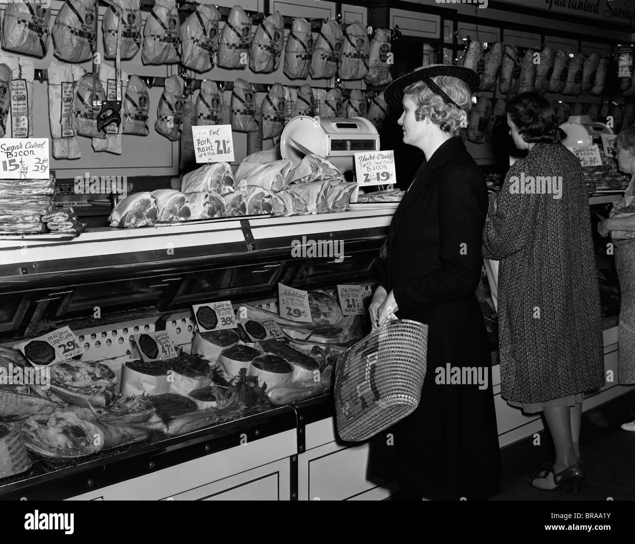 1940ER JAHRE FRAUEN IN DER METZGEREI IN VITRINE VON FLEISCH Stockfoto