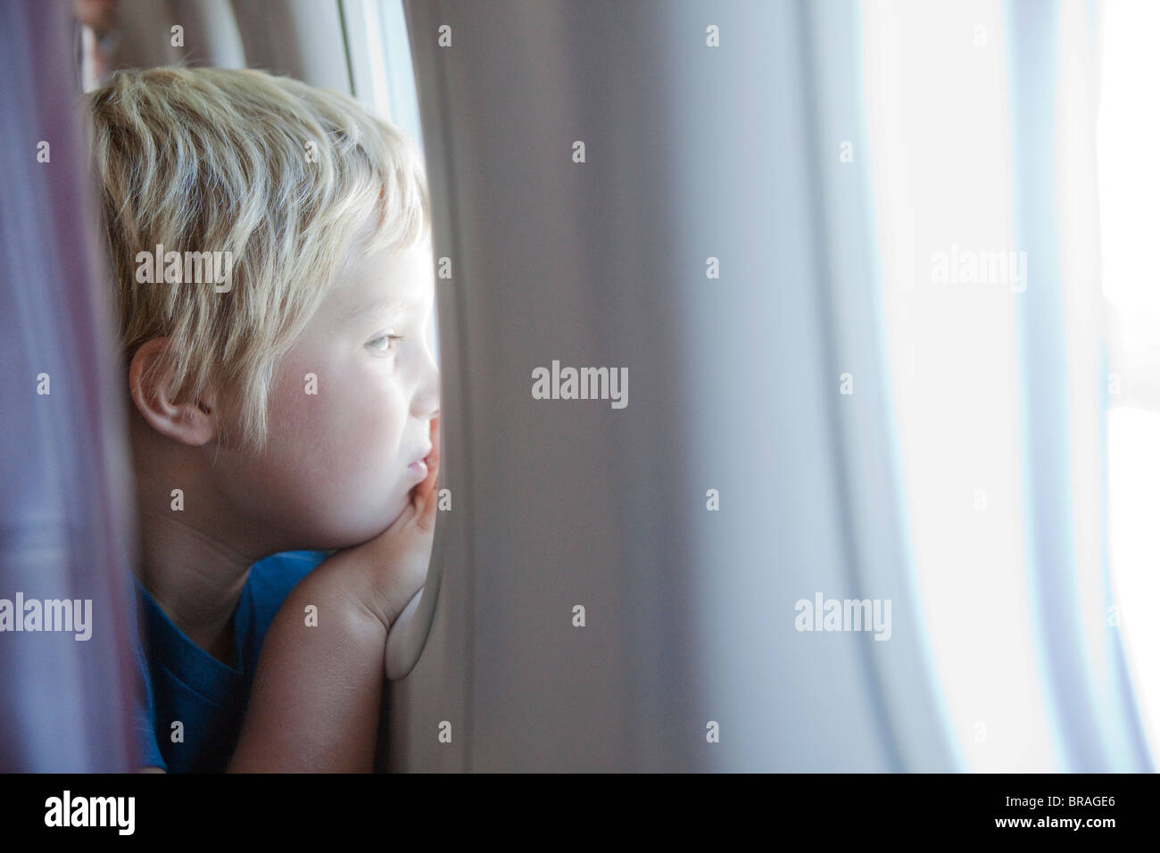 Kleiner Junge starrt Flugzeugfenster Stockfoto