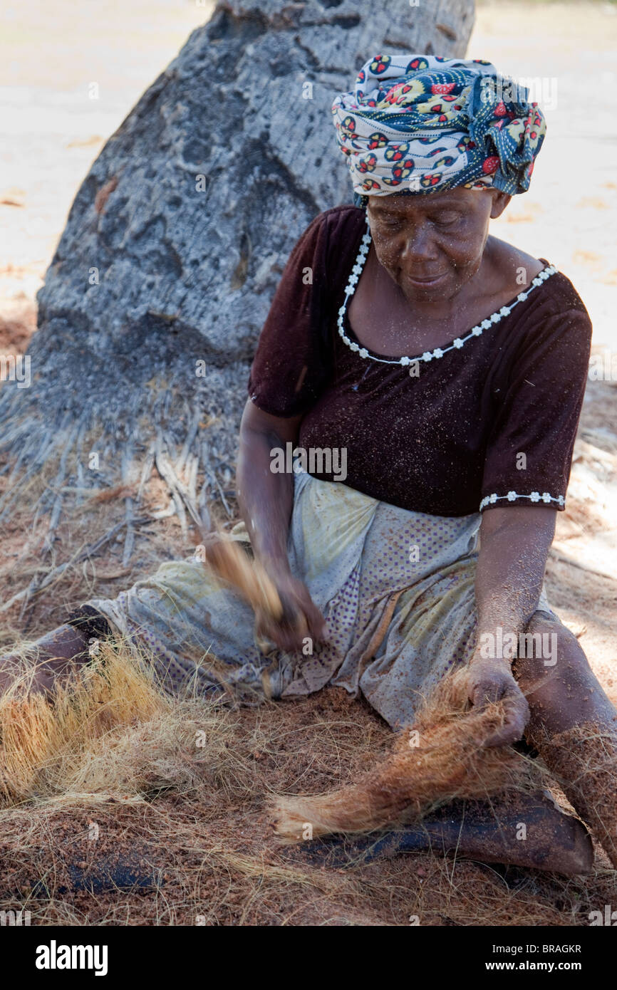 Kizimkazi, Dimbani, Sansibar, Tansania. Frau gegen Kokosnussschalen, Kokos, um Seile zu produzieren. Stockfoto
