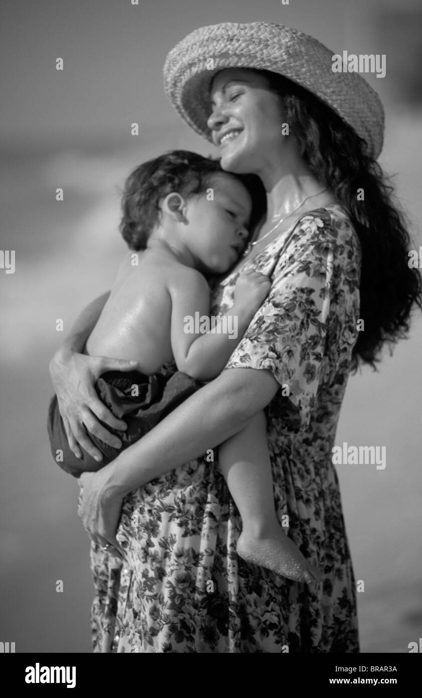 Schön schwanger hispanische Mutter mit ihrem kleinen Sohn mit Liebe zusammen am Strand mit Wellen Stockfoto