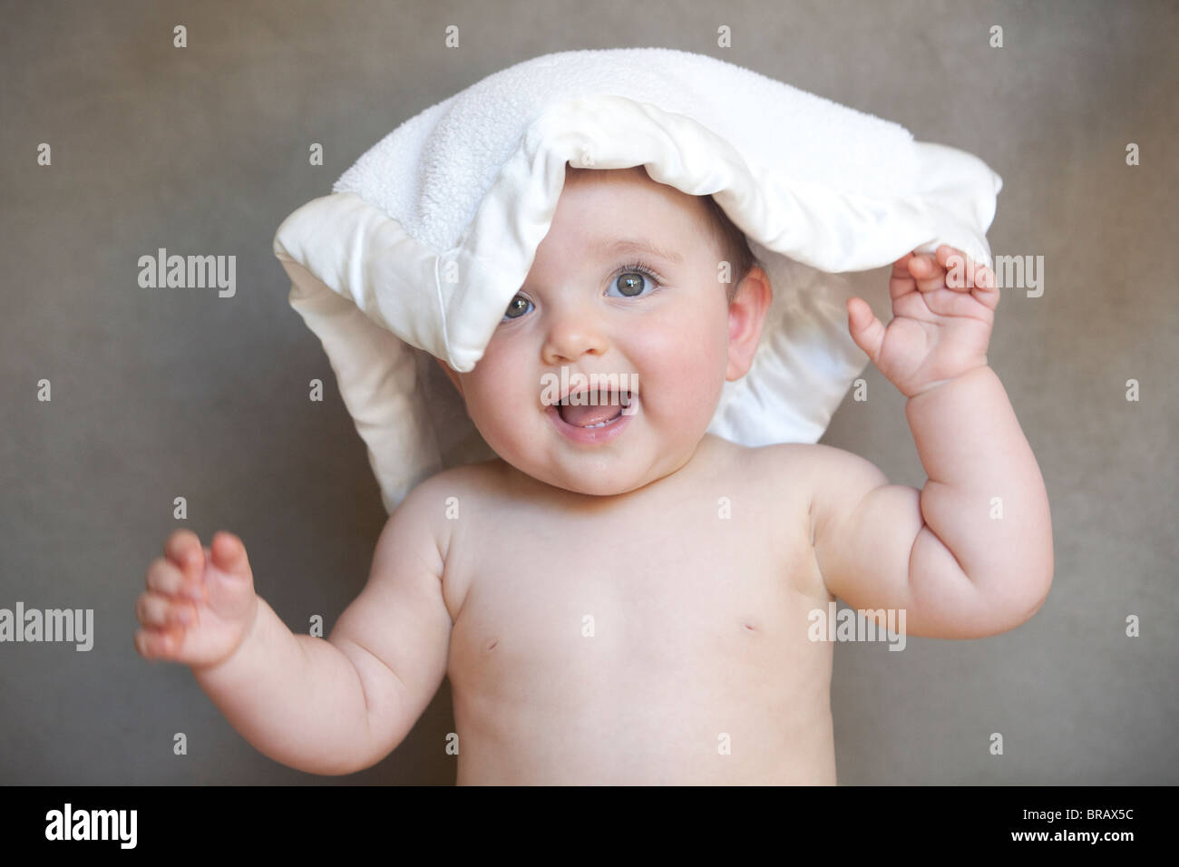 Baby lächelnd mit einer Decke auf den Kopf Stockfoto