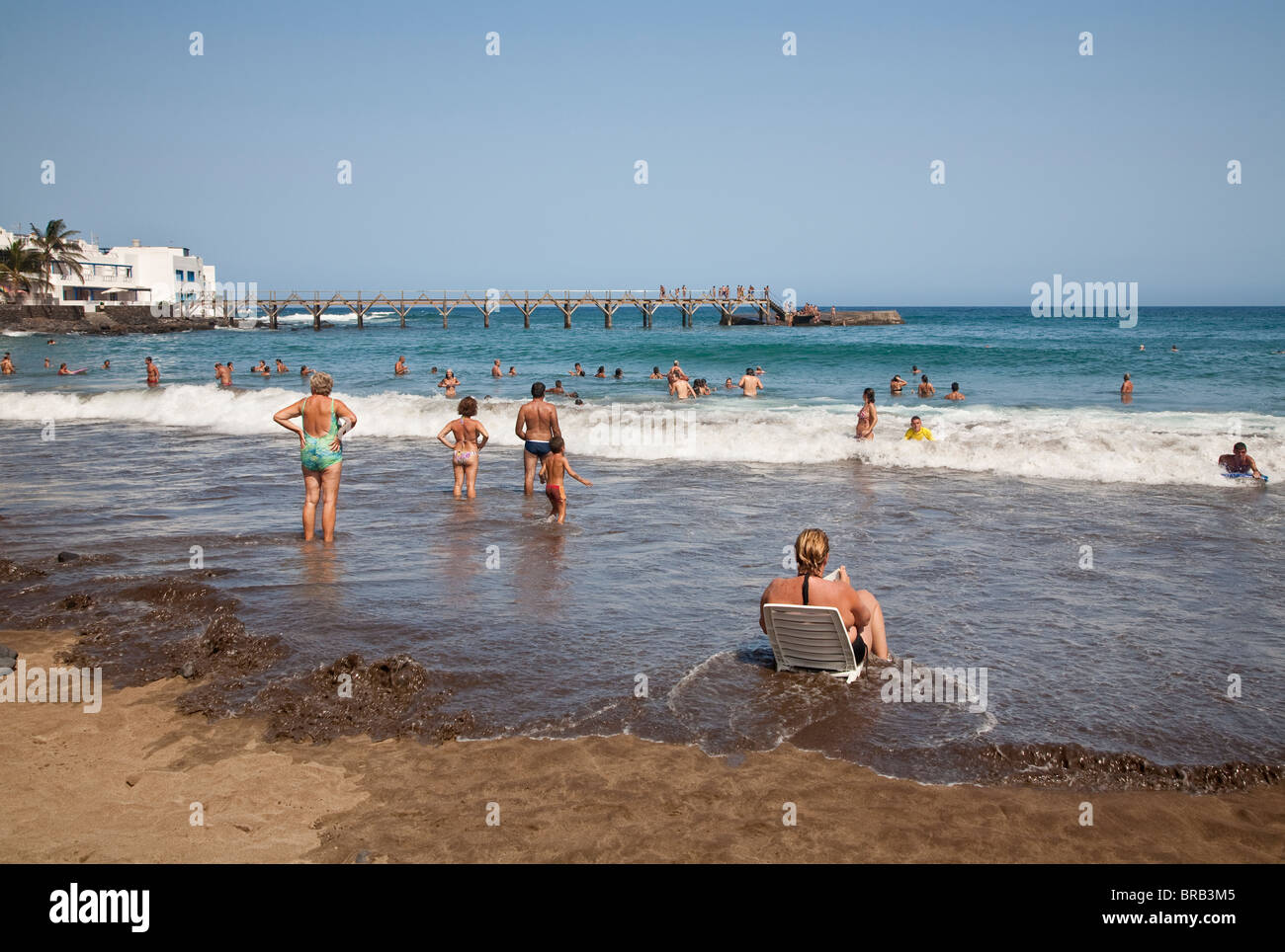 Sonnenbaden, Paddeln, Schwimmen und Surfen am Strand von Playa Garita, Arrieta, Lanzarote Stockfoto