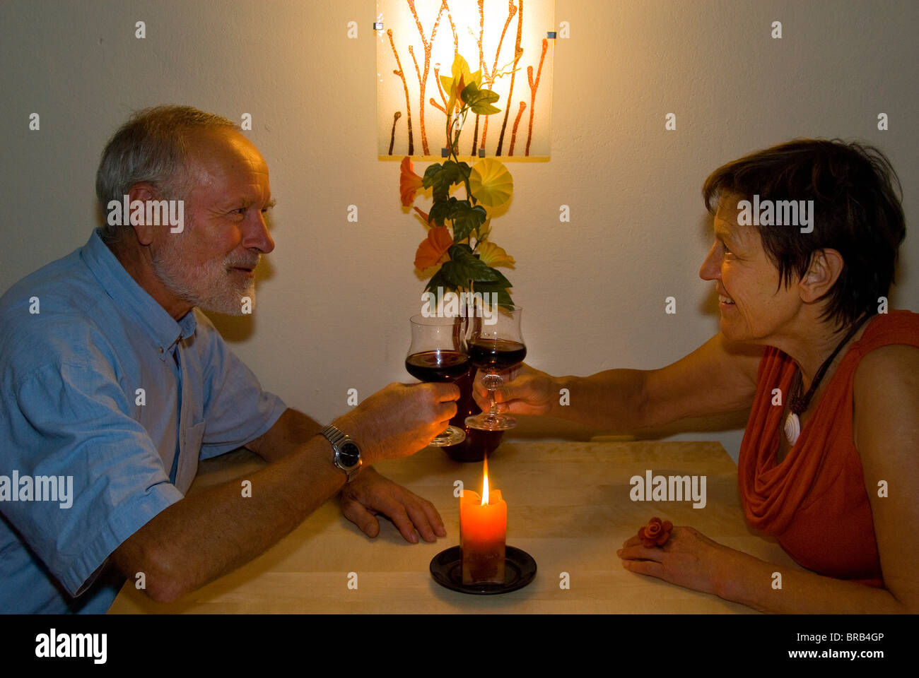 Älteres Ehepaar mit einem Glas Wein bei Kerzenschein Stockfoto