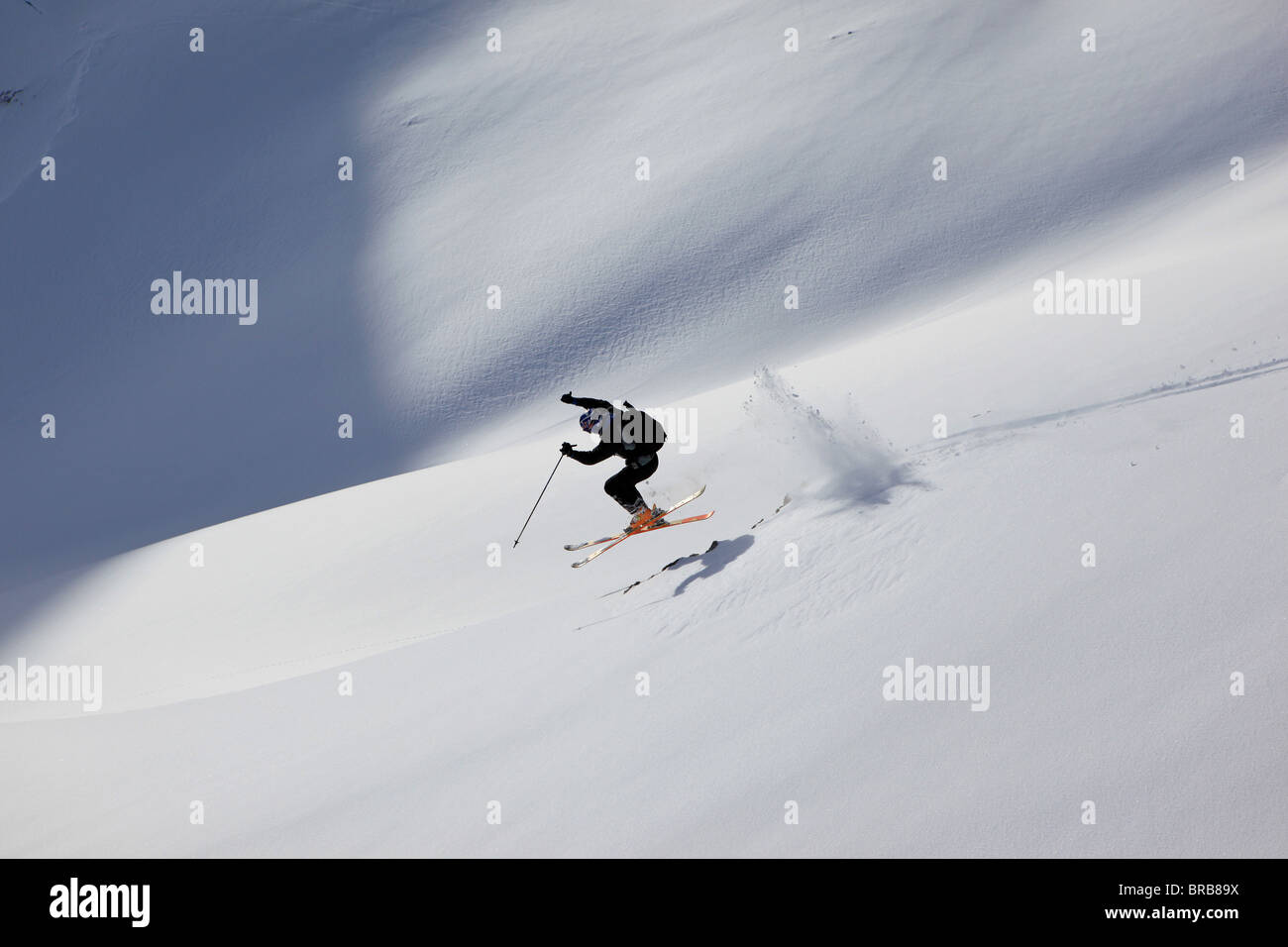 Ein Skifahrer springt über einige Felsen in das Pulver auf einen Val Gardena off Piste Hang Stockfoto